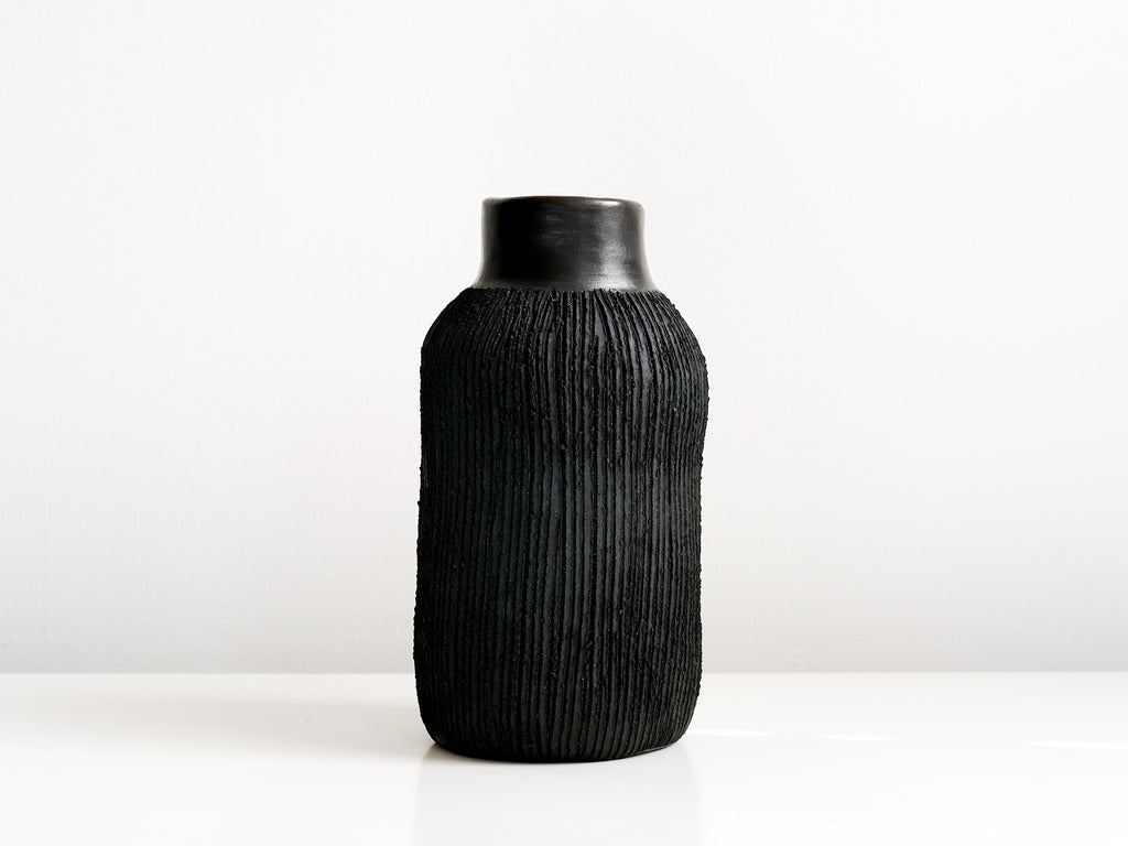 Black textured pottery vase on a white background