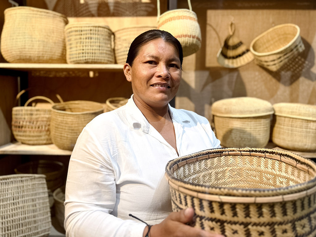 Woman holding a woven basket in front of shelves with more baskets