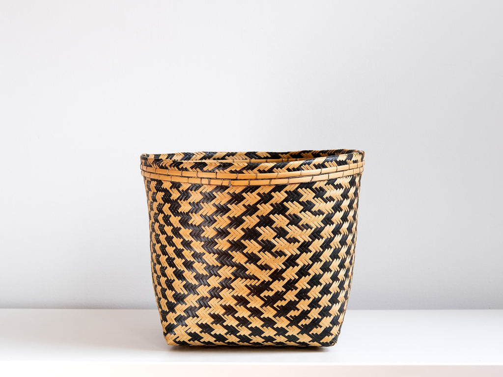 Woven basket with black and brown pattern on a white background