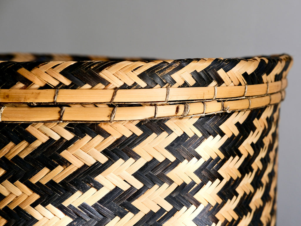 Close-up of a black and natural woven basket on a gray background