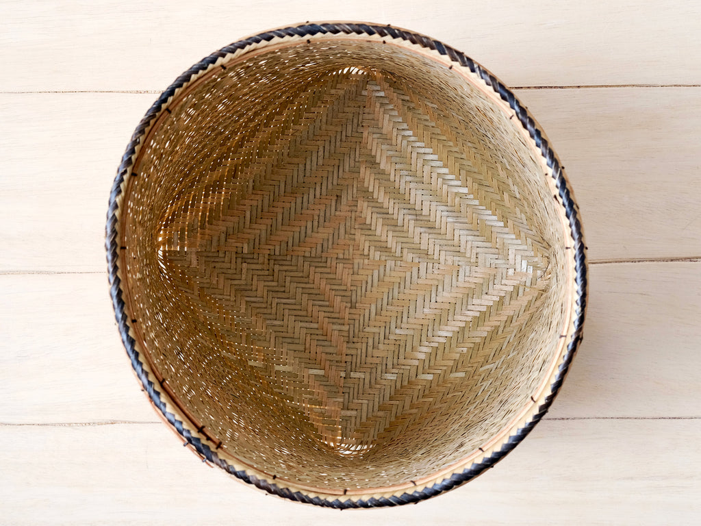 Woven basket with a diamond pattern on a light wooden surface
