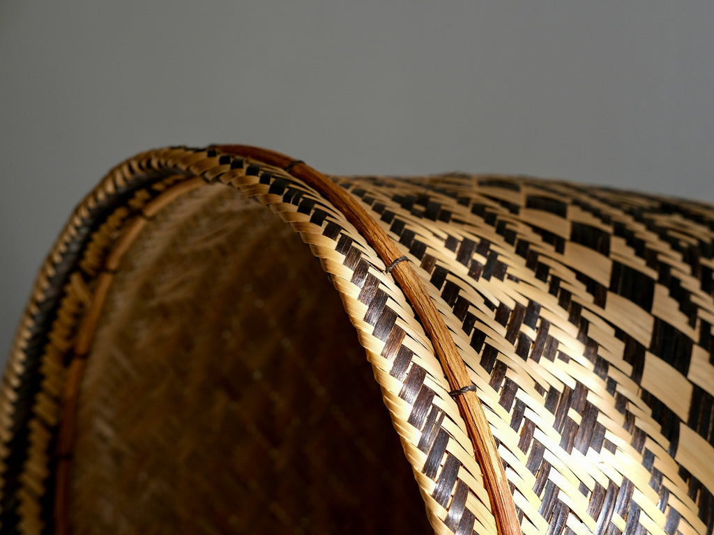 Close-up of a woven basket with a geometric pattern on a plain background