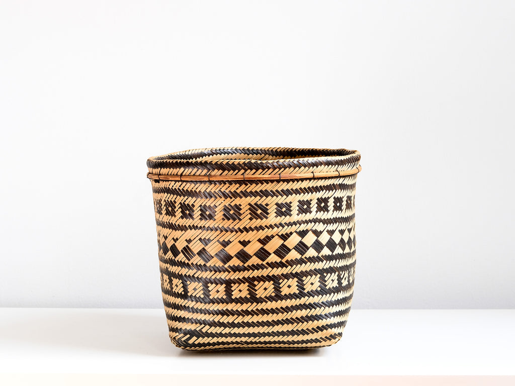 Woven basket with black and beige pattern on a white background